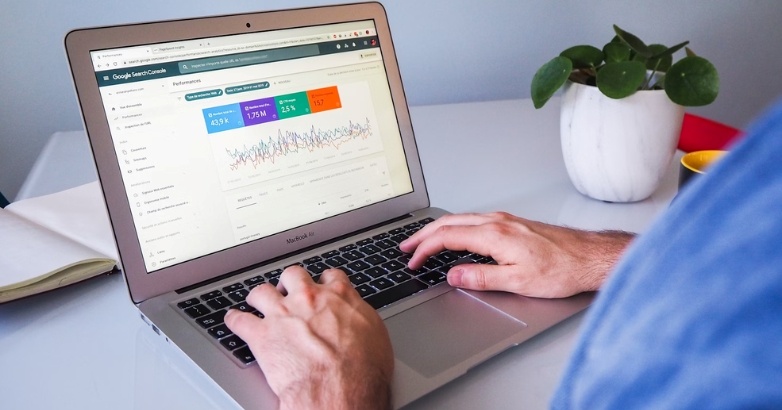 A person engaged in typing on a laptop, featuring graphs on hospitality advertising analytics, representing the paid vs. organic strategies.