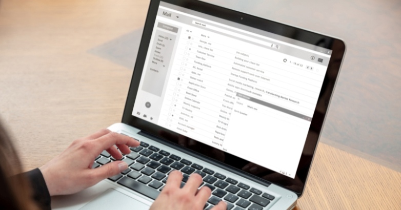 Individual using a laptop to compose an email regarding hotel marketing examples emphasizing personalization and segmentation.