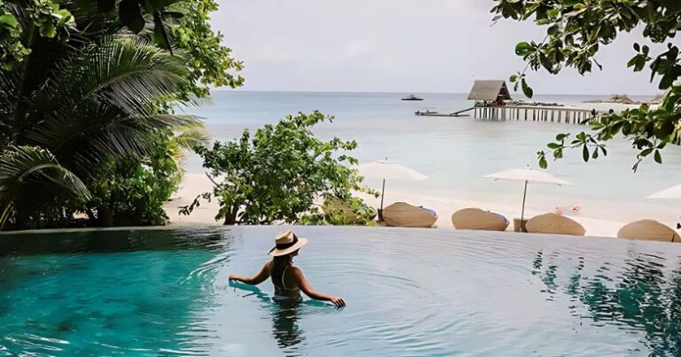 A woman wearing a stylish hat relaxes in a resort pool, embodying the latest hotel trends in leisure and luxury.