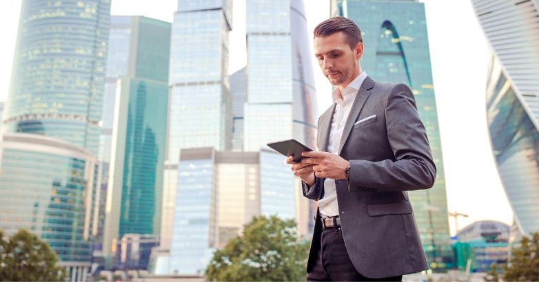 A man in a suit checks his phone, reflecting on Facebook advertising strategies for hotels and conversion optimization.