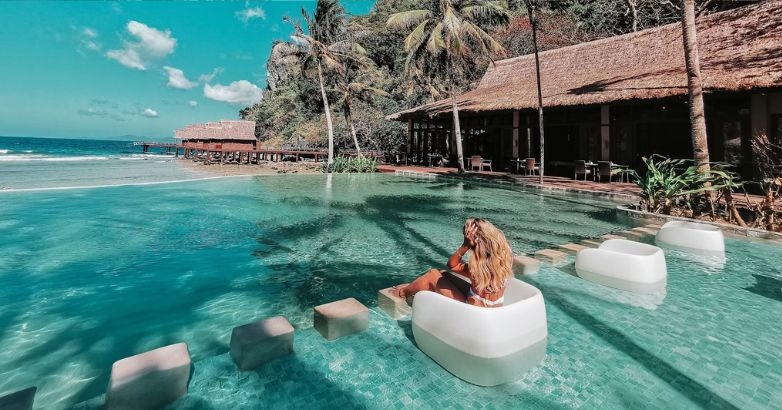 A woman enjoys leisure time in a pool located near the beach, showcasing a picturesque hotel setting with partnership & affiliate marketing.