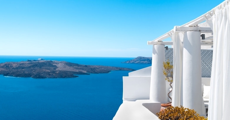 Stunning sea and Santorini island view from a luxury hotel balcony, highlighting the picturesque local landscape.