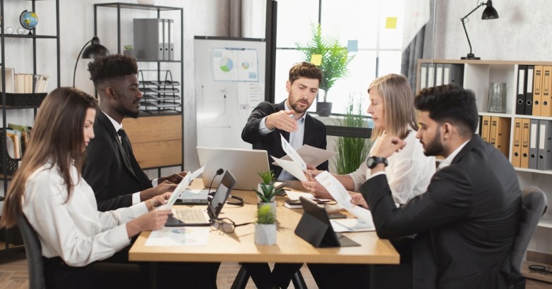 A team of professionals gathered around a table with documents, collaborating on strategies for hotel video marketing.