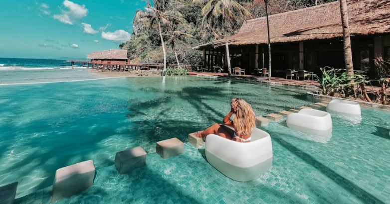 A woman enjoys a tranquil moment sitting on a chair in the water at a resort, surrounded by a peaceful and scenic view.