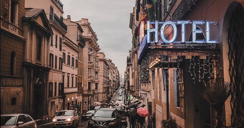 A street with parked cars and a visible hotel sign, representing challenges and changes in hotel marketing strategies.