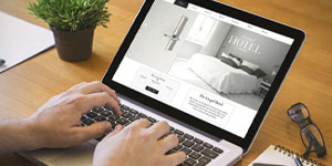 A person engaged with a laptop, reviewing a website related to hotel digital marketing planning.