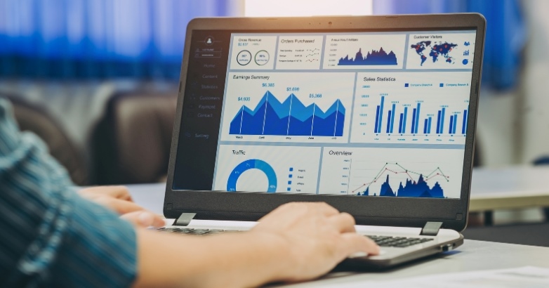 A performance dashboard on a laptop shows revenue, traffic sources, and booking trends, representing how hotels use data to optimize marketing and pricing strategies.