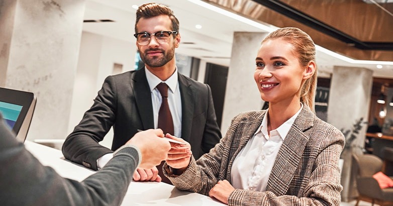 A man and woman in front at a desk, illustrating a business agreement in the context of travel advertising.
