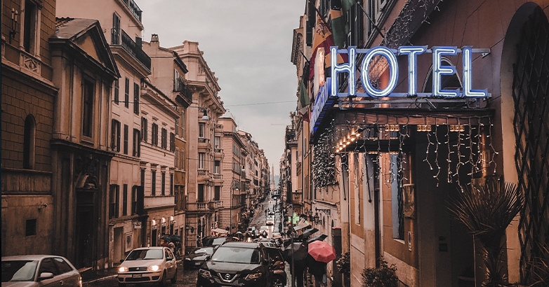 A street with parked cars and a hotel sign, representing themes of hotel branding and marketing.