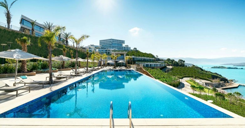 The hotel pool area features lounge chairs and umbrellas, providing a comfortable space for relaxation and leisure.