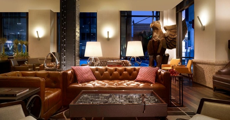 Hotel lobby featuring leather couches and a decorative statue, showcasing elegant branding and inviting atmosphere.