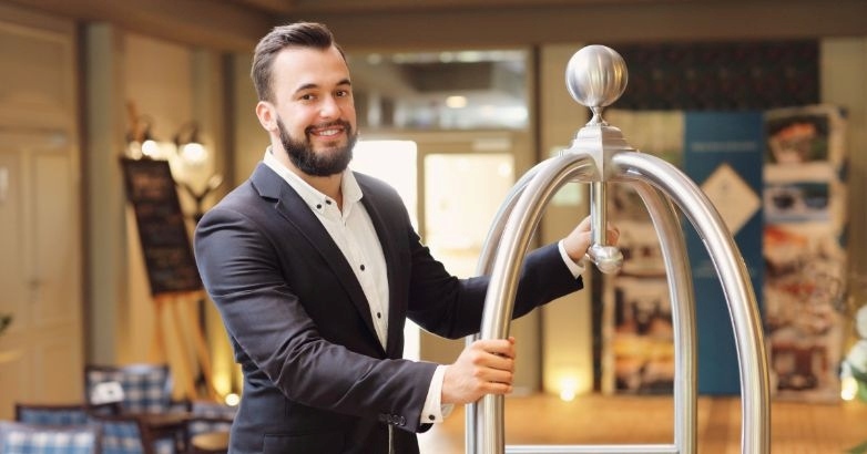 A man dressed in a suit holds a metal bar, illustrating the focus on brand-centered communication for hotel staff training.