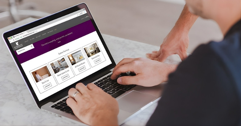 A man at a laptop with a purple background, concentrating on UX and conversion optimization for a hotel website redesign.