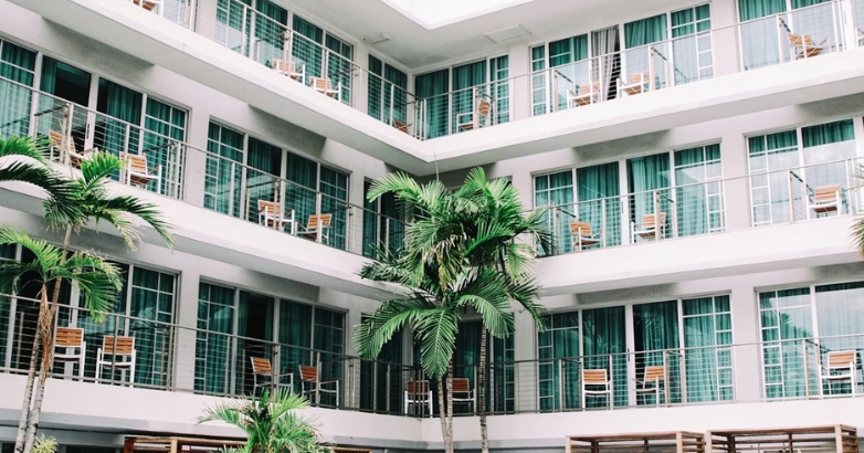 A modern hotel with balconies surrounded by palm trees, representing ideal settings for digital marketing in the hospitality sector.