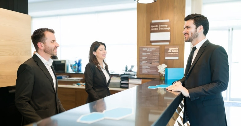 Hotel staff speaking with a guest at the front desk, supporting lead generation for hotels
