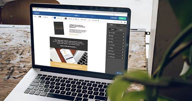 Laptop on a wooden desk displaying a website builder.