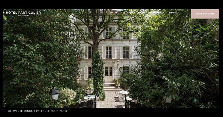 A charming hotel surrounded by lush greenery, featuring a classic facade and outdoor seating area.