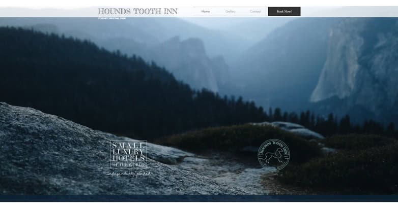 A scenic view of mountains and forests, with a rocky foreground. The image promotes Hounds Tooth Inn, featuring a serene atmosphere.