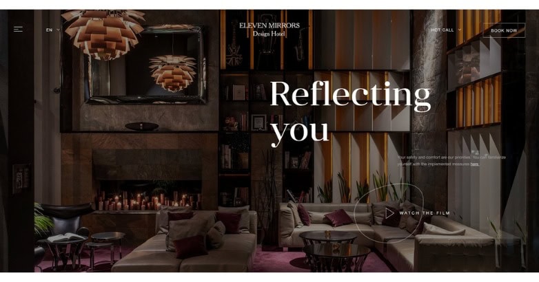 A stylish hotel lobby featuring modern decor, a cozy seating area, and elegant lighting. Text overlay reads Reflecting you.