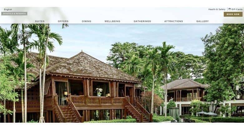 A serene resort with wooden architecture surrounded by lush greenery and palm trees.