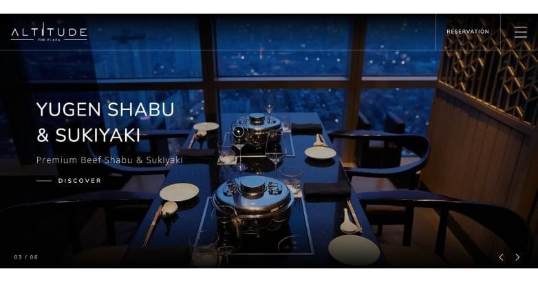 A stylish dining setup featuring shabu and sukiyaki pots, with elegant tableware and a city view at night.