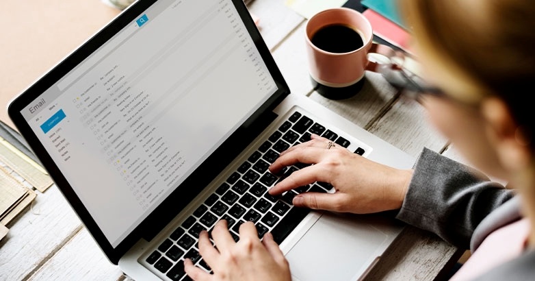 A woman engaged in typing on a laptop, working on building a high-quality email list for hospitality marketing.