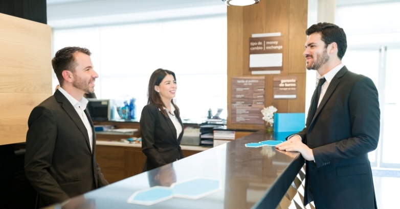 A man and woman are at a hotel front desk, emphasizing the significance of lead generation in the hospitality industry.