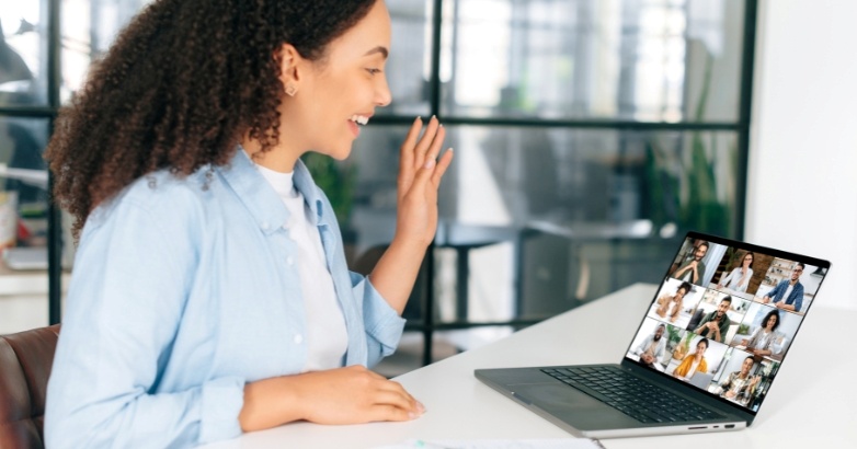 A woman converses on a laptop with a group displayed on the screen, participating in a virtual event about hotel lead generation.