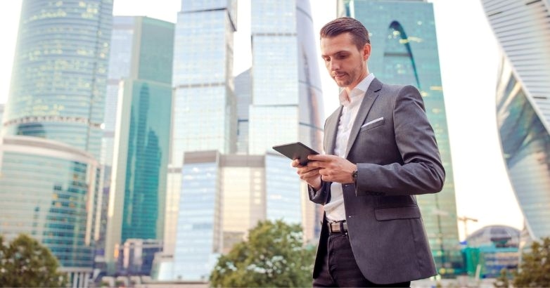 A man in a suit checks his phone, reflecting on Facebook advertising strategies for hotels and conversion optimization.