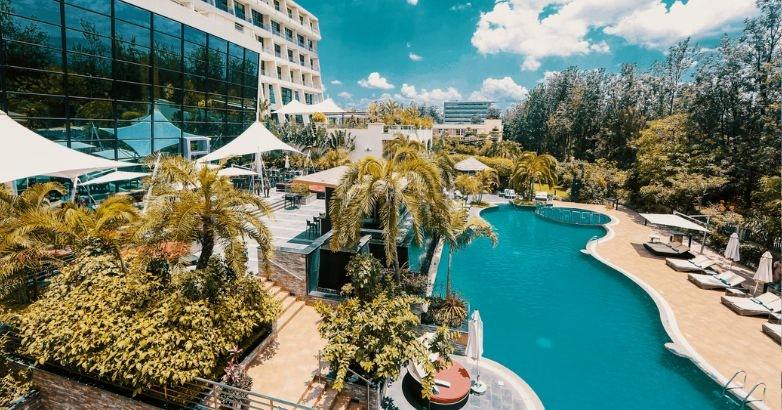 A tranquil hotel pool scene with crystal-clear water, surrounded by comfortable seating and vibrant landscaping.
