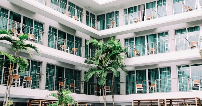 A contemporary structure with balconies and palm trees, highlighting the future of sustainability in hotel marketing.