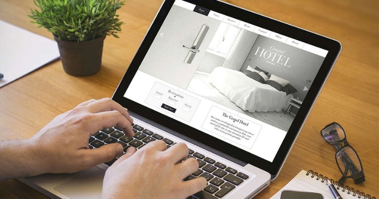 Individual focused on typing on a laptop, representing the future of hotel website design and core design trends.