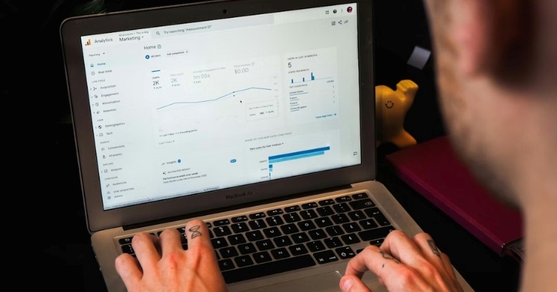 Individual working on a laptop showing a graph for launching a Google Hotel Ads campaign and tracking bids.