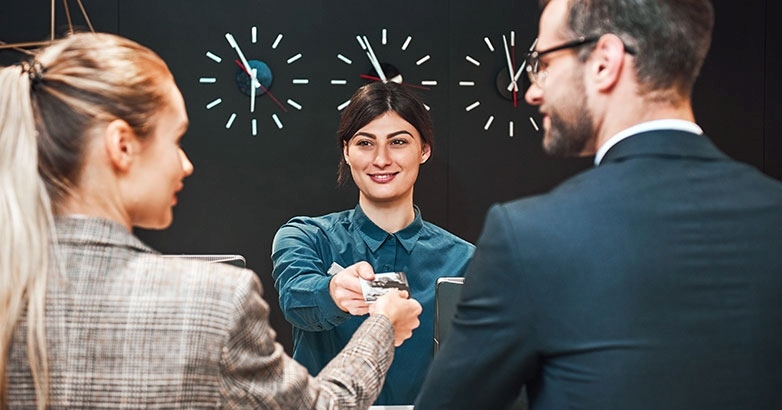 A man and woman engage in a handshake at a desk, focusing on sustainability storytelling in hospitality marketing.