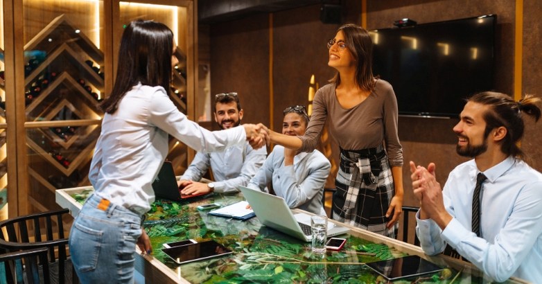 Business partners shaking hands at a conference table, emphasizing hotel branding and customer ambassador programs.