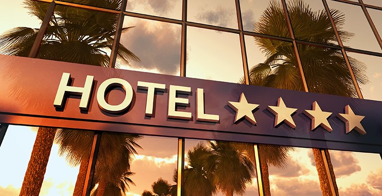 Hotel sign surrounded by palm trees, emphasizing the importance of effective hotel marketing services.